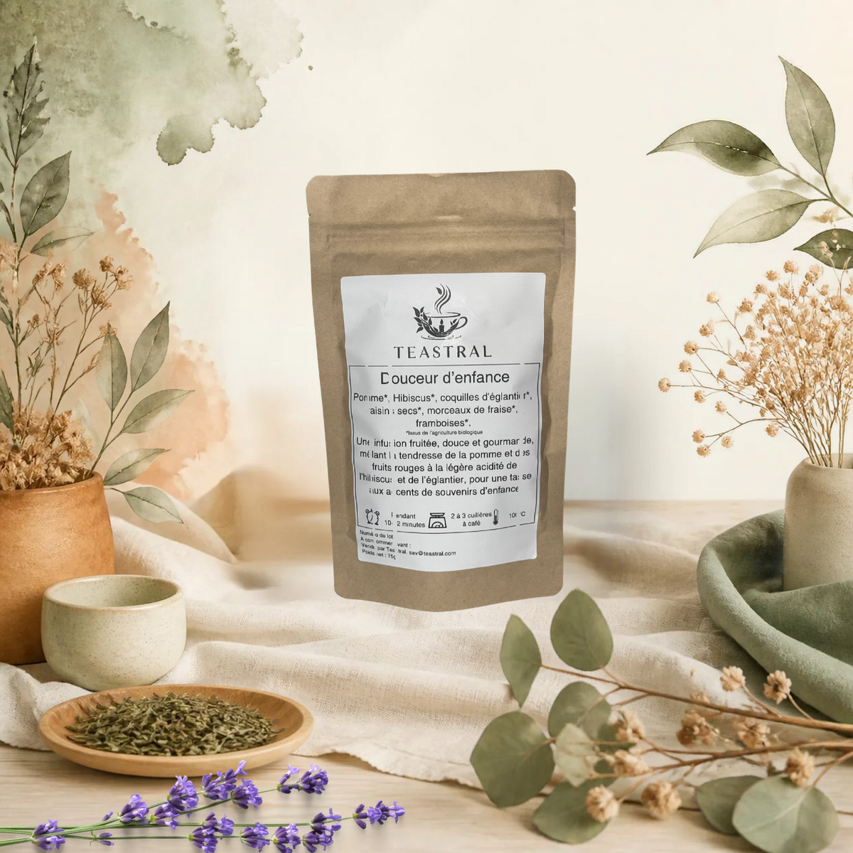 Sachet kraft de l’infusion bio Douceur d’enfance Teastral, posé sur un lin beige avec eucalyptus, lavande et coupelle de plantes séchées