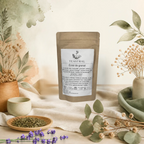 Sachet kraft de l’infusion bio Éclat de grenat Teastral, posé sur un lin beige avec eucalyptus, lavande et coupelle de plantes séchées