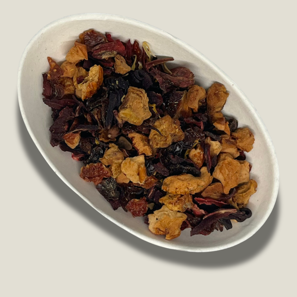 Infusion bio Éclat rouge en vrac dans une coupelle blanche : morceaux de pomme séchée dorés et pétales d’hibiscus rouge foncé