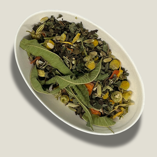 Infusion de plantes bio Équilibre intérieur en vrac dans une coupelle blanche : longues feuilles de verveine, fleurs de camomille, graines de fenouil et morceaux de carotte