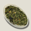Infusion de plantes bio Esprit libre en vrac dans une coupelle blanche : feuilles vertes séchées, graines de fenouil et baie bleu foncé