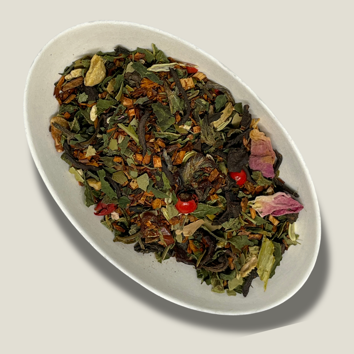 Mélange bio Aura féminine en vrac dans une coupelle blanche : rooibos, feuilles vertes, pétales de rose, baies rouges et morceaux de gingembre