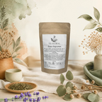 Sachet kraft du thé noir Assam bio Éclat d’agrumes Teastral, posé sur un lin beige avec eucalyptus, lavande et coupelle de plantes séchées