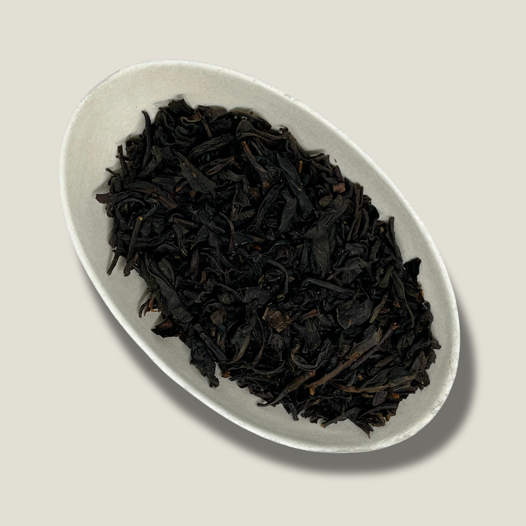 Feuilles de thé noir bio Élégance britannique en vrac dans une coupelle blanche, feuilles torsadées brun très foncé