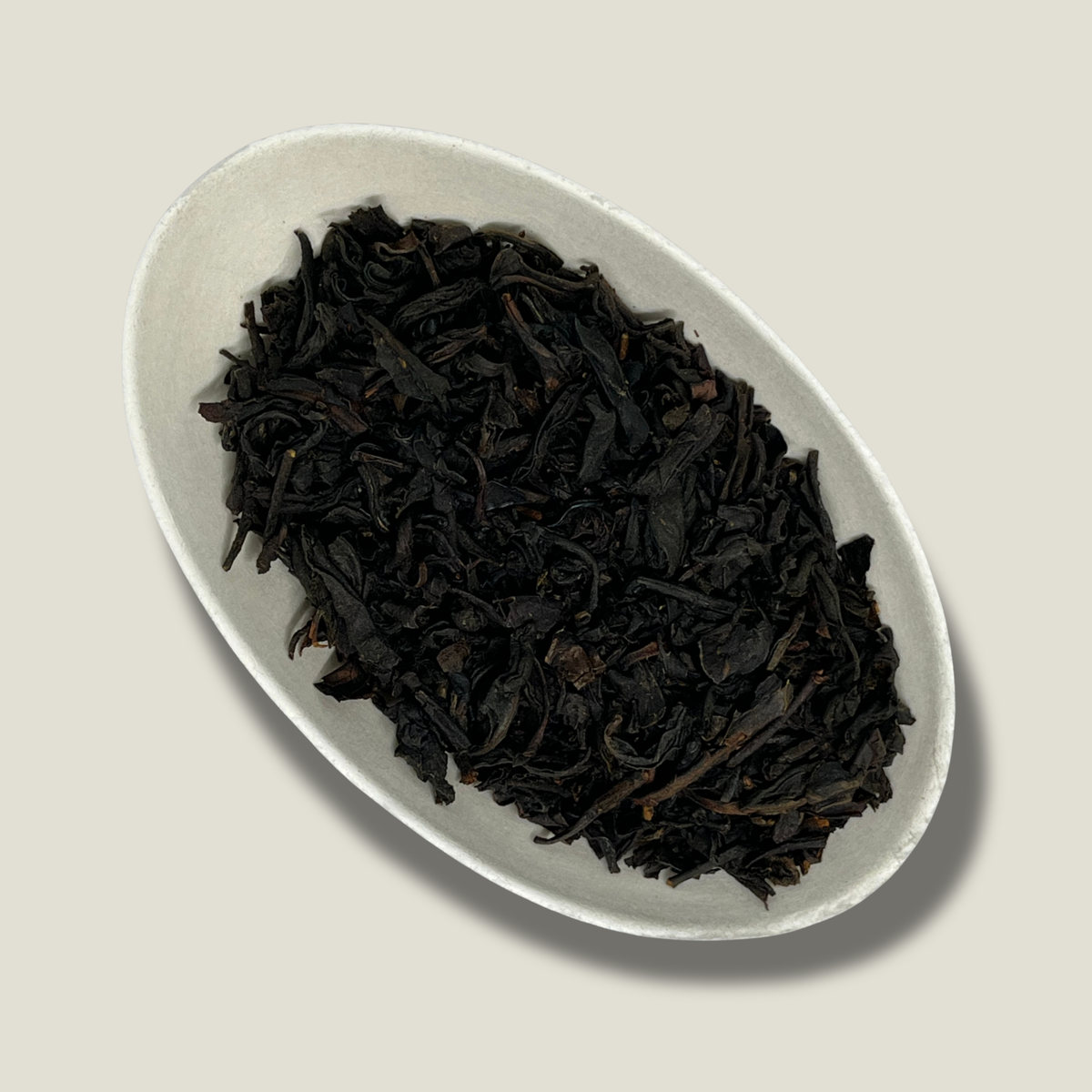 Feuilles de thé noir bio Élégance britannique en vrac dans une coupelle blanche, feuilles torsadées brun très foncé