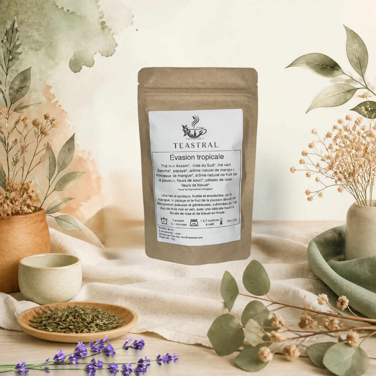Sachet kraft du mélange de thé noir et thé vert bio Évasion tropicale Teastral, posé sur un lin beige avec eucalyptus, lavande et coupelle de plantes séchées