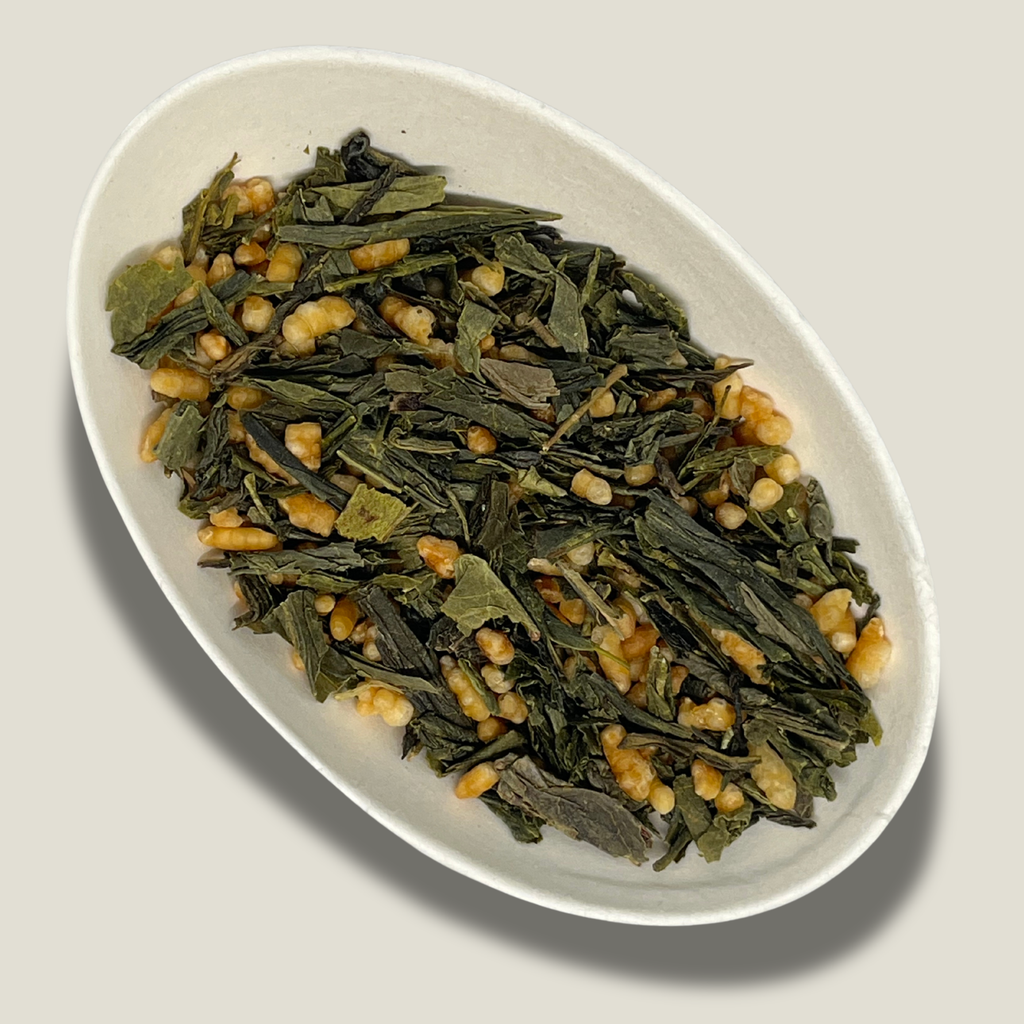 Thé vert Genmaicha bio en vrac dans une coupelle blanche : feuilles vertes allongées et grains de riz torréfié soufflés, dorés