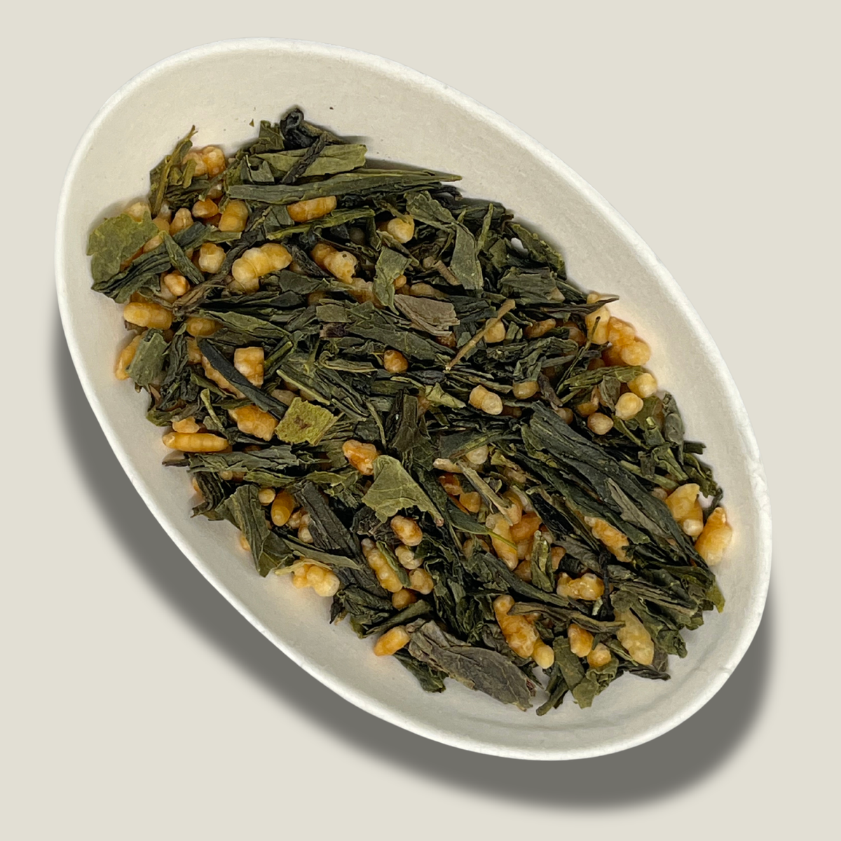 Thé vert Genmaicha bio en vrac dans une coupelle blanche : feuilles vertes allongées et grains de riz torréfié soufflés, dorés