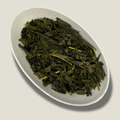 Feuilles de thé vert Sencha bio aromatisé à la bergamote en vrac dans une coupelle blanche