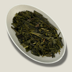 Feuilles de thé vert Sencha bio aromatisé à la bergamote en vrac dans une coupelle blanche