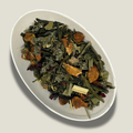 Thé vert Sencha bio Énergie douce en vrac dans une coupelle blanche : feuilles vertes, brins de citronnelle, morceaux de fruits séchés orangés et pétales rouges