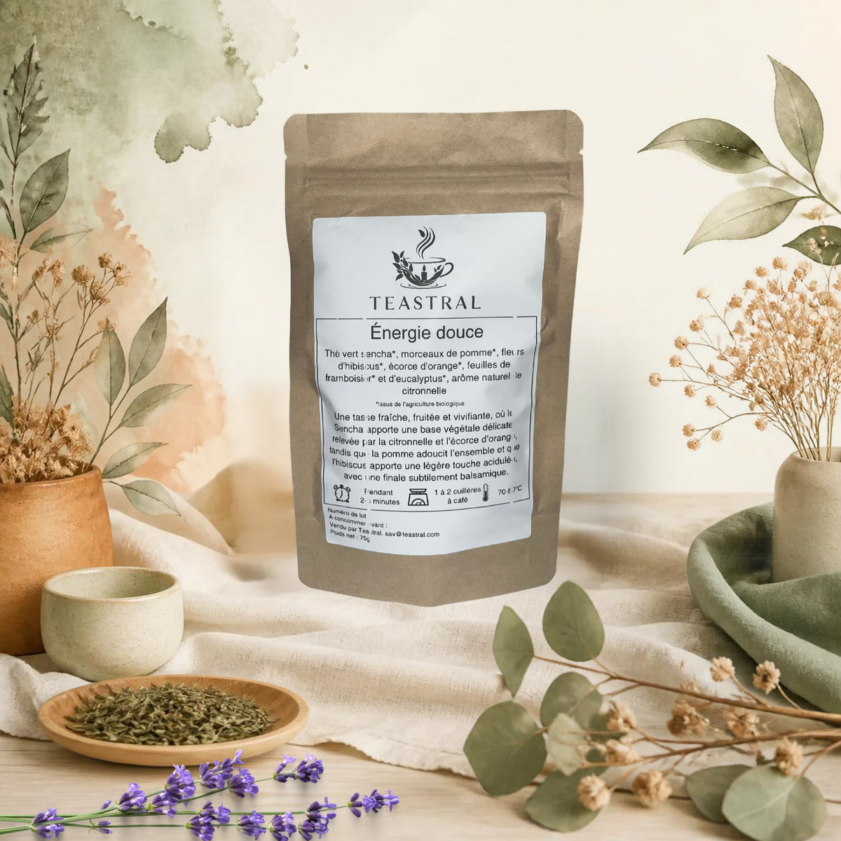 Sachet kraft du thé vert Sencha bio Énergie douce Teastral, posé sur un lin beige avec eucalyptus, lavande et coupelle de plantes séchées