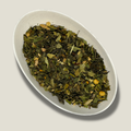 Thé vert Sencha bio Force intérieure en vrac dans une coupelle blanche : feuilles vertes, morceaux de gingembre clairs et petites graines jaune orangé